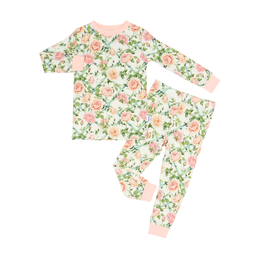 A two-piece children's pajama set featuring a long-sleeve top and matching pants with a pink and green floral rose pattern on a white background, finished with solid light pink ribbed cuffs and collar.
