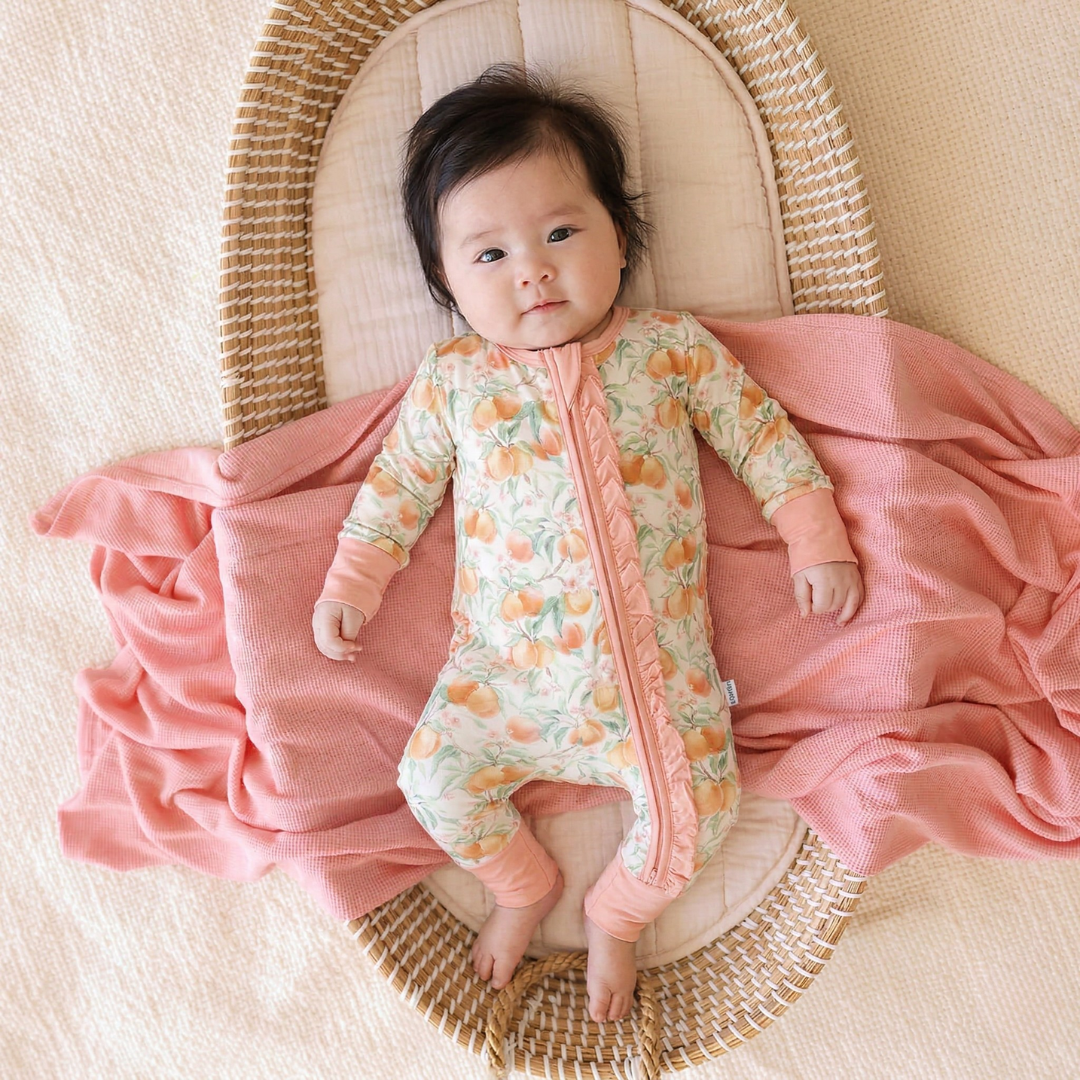 Baby lying on a pink blanket in a wicker basket