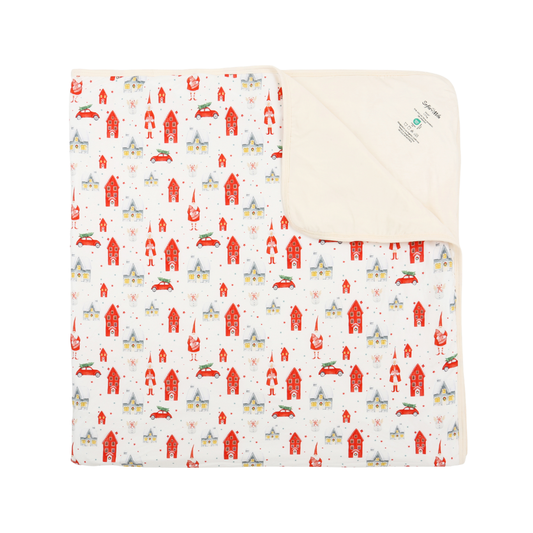 A folded baby blanket with a white background and a repeating pattern of red, gray, and yellow farmhouses and chickens, showing a soft cream-colored fleece backing.