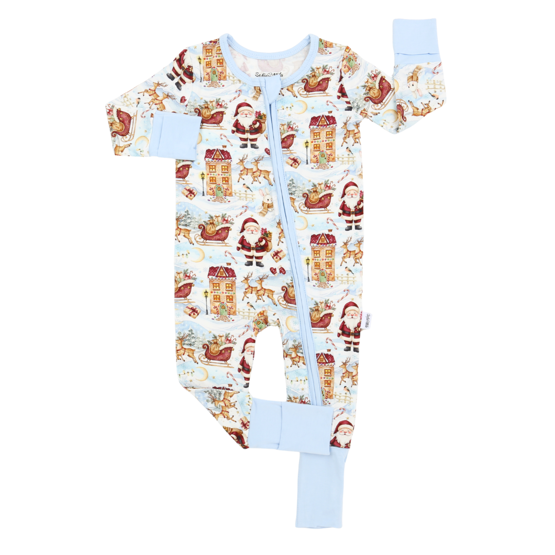 A baby long-sleeve footed sleeper with a light blue zipper, featuring a festive Christmas print of Santa Claus, sleighs, gingerbread houses, and reindeer on a white background, with light blue cuffs and leg cuffs.