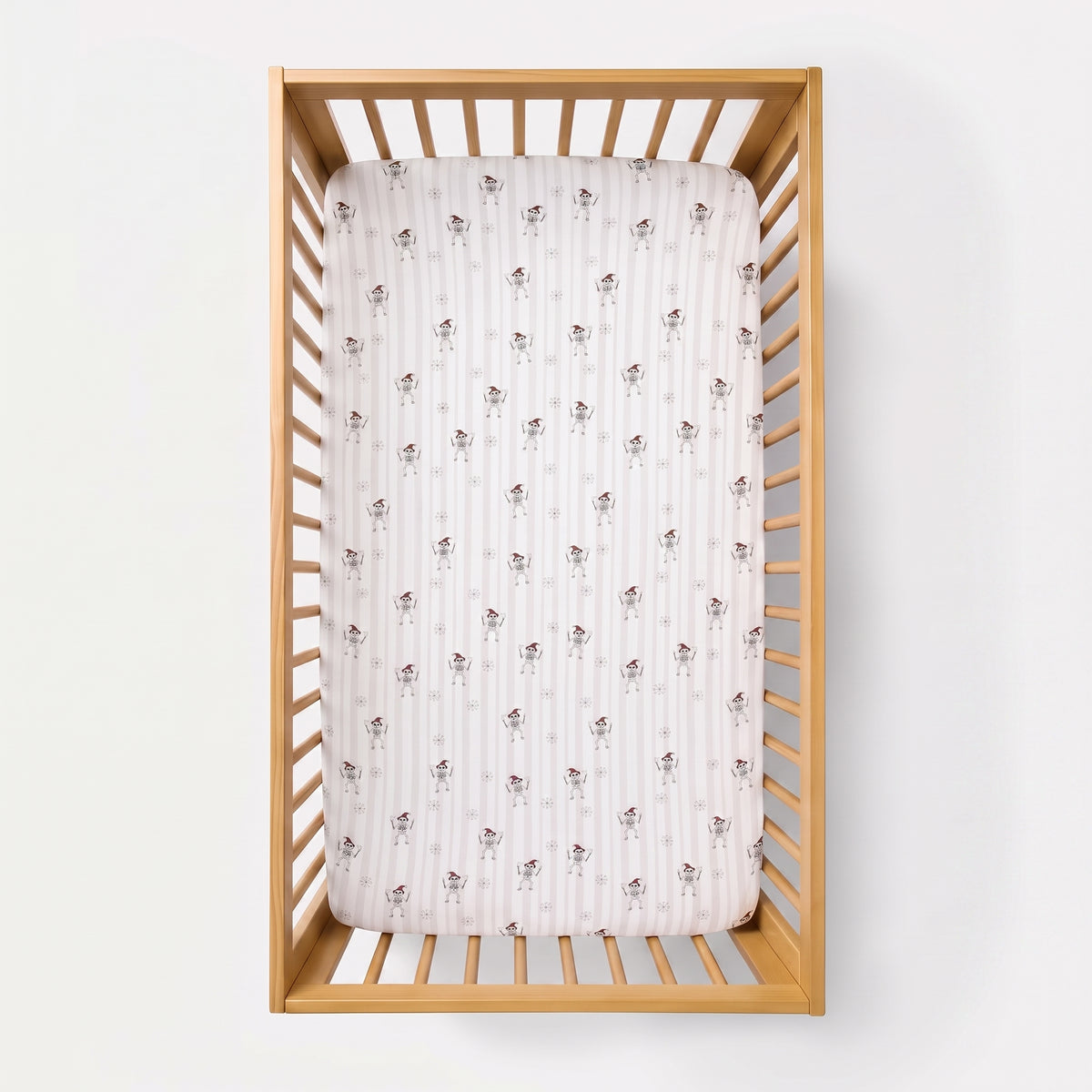 A fitted crib mattress with a white and pink striped pattern and small brown bunny motifs, shown inside a light natural wood crib against a white background.