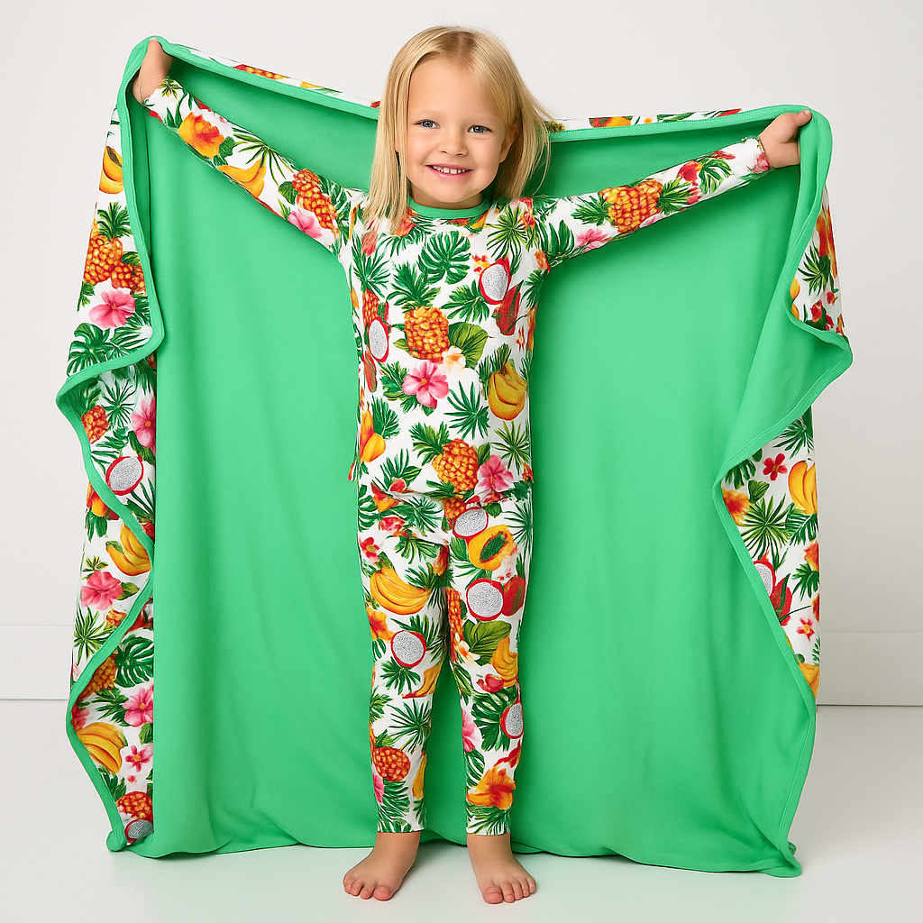 Child wearing a tropical print onesie with a matching green blanket