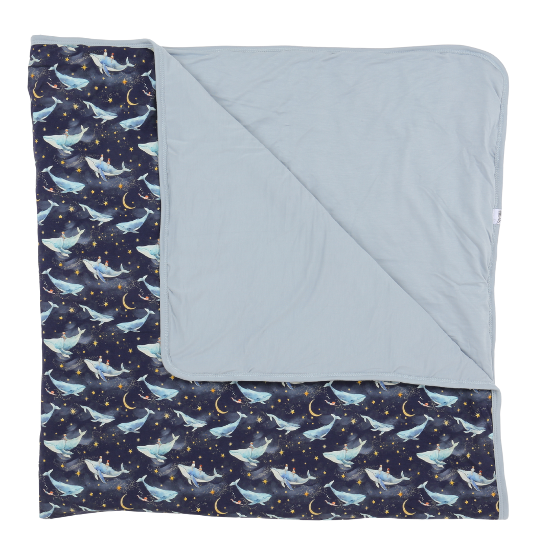 Blanket with whale pattern on one side and solid color on the other, folded neatly.