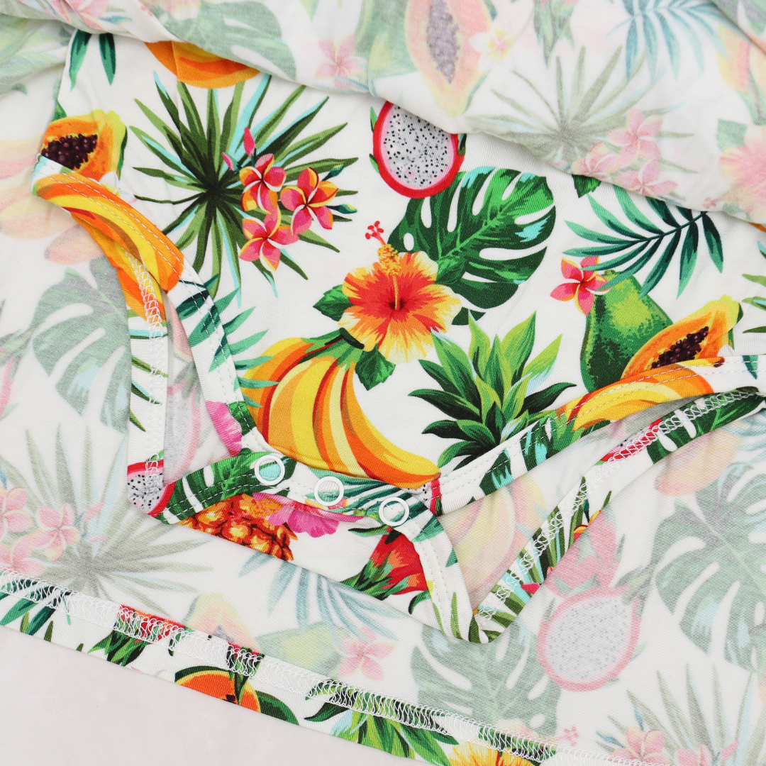 Tropical fruit and leaf patterned fabric with bananas, pineapples, and flowers.