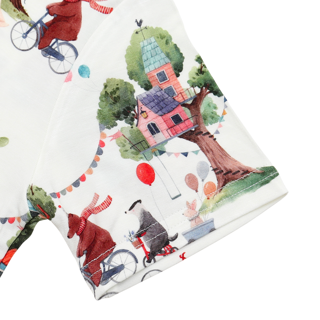Fabric with colorful cartoon-style illustrations of a house, trees, and people on bicycles.