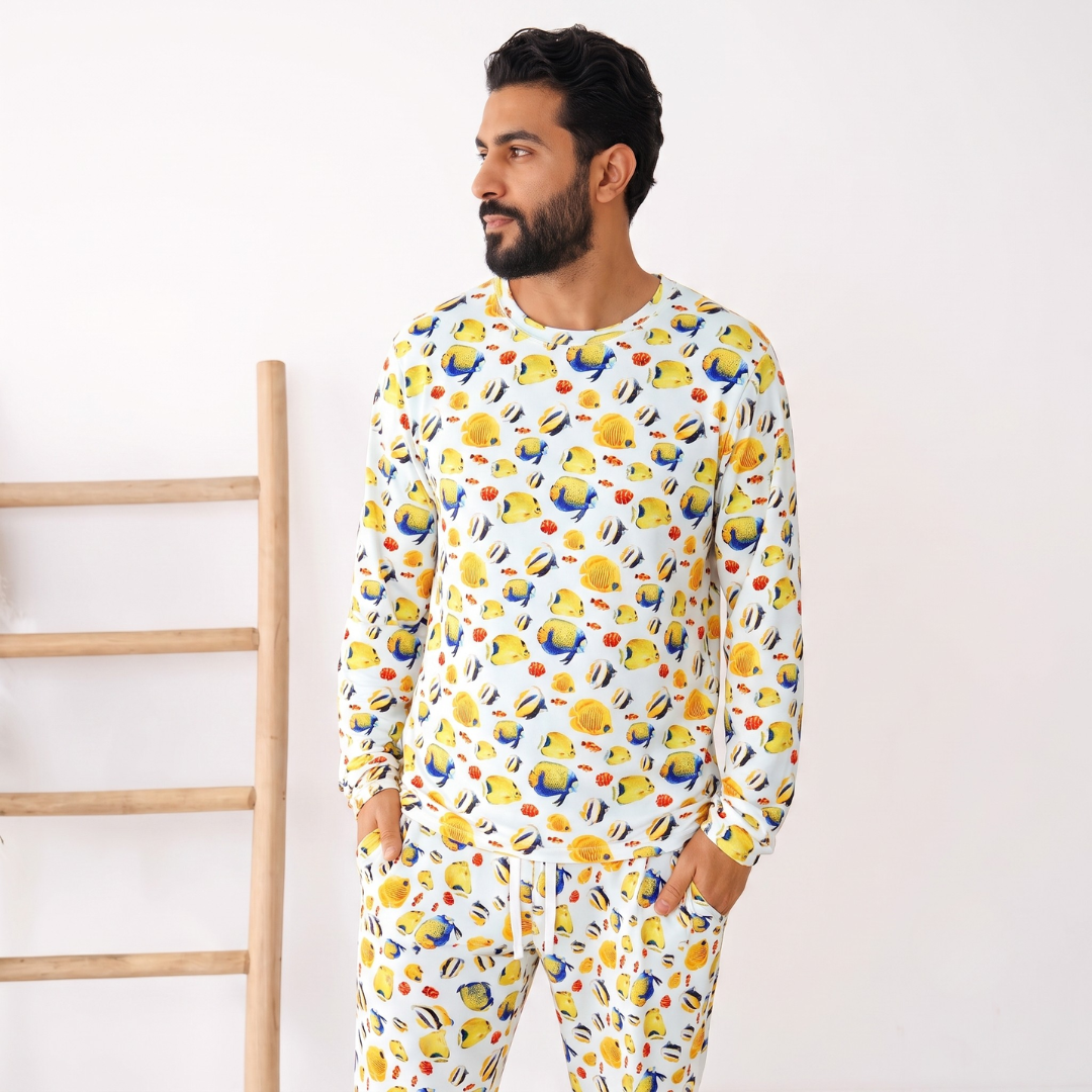 Man wearing a colorful onesie with a pattern of cartoon characters against a white background.
