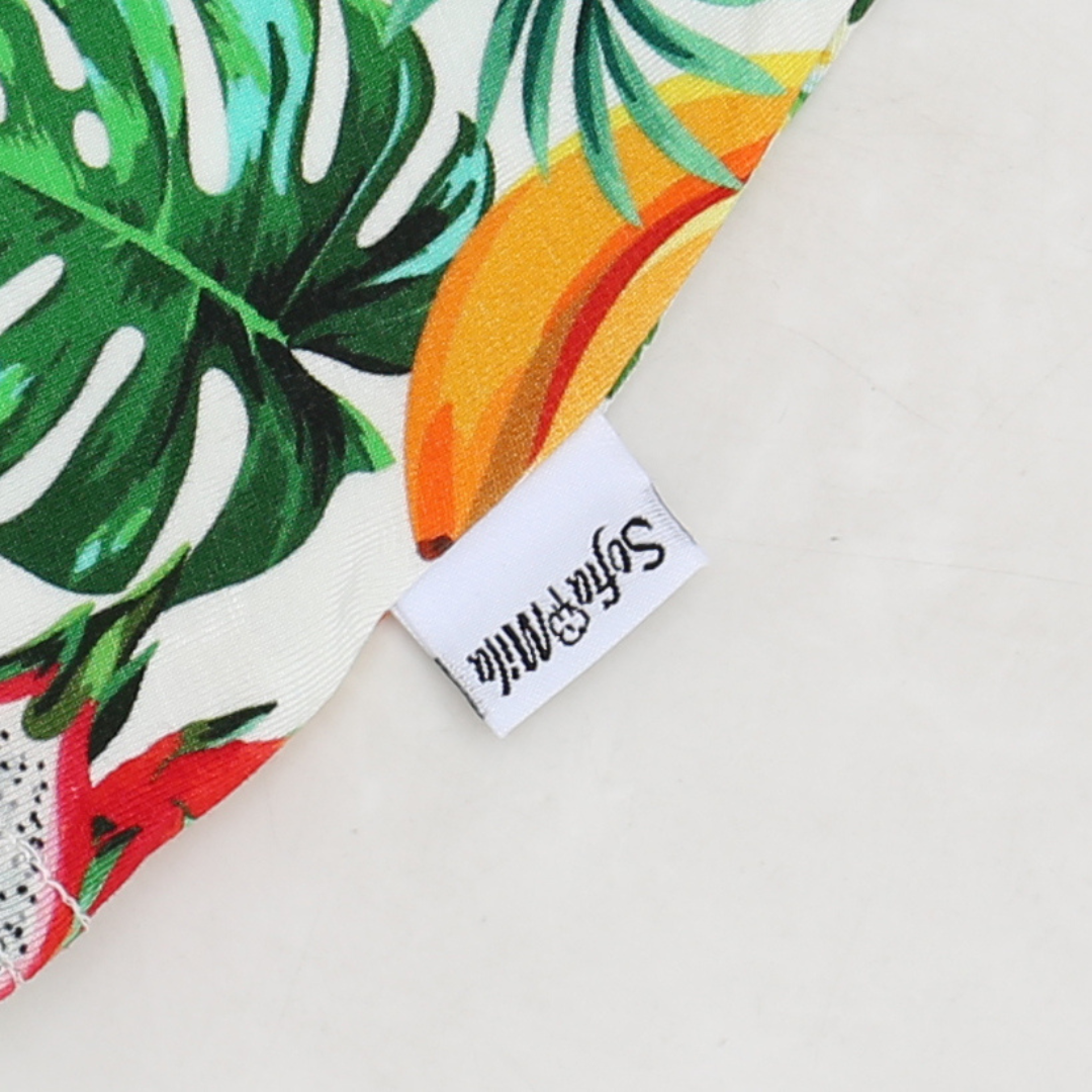 Fabric with tropical leaf pattern and a visible brand label on a light background