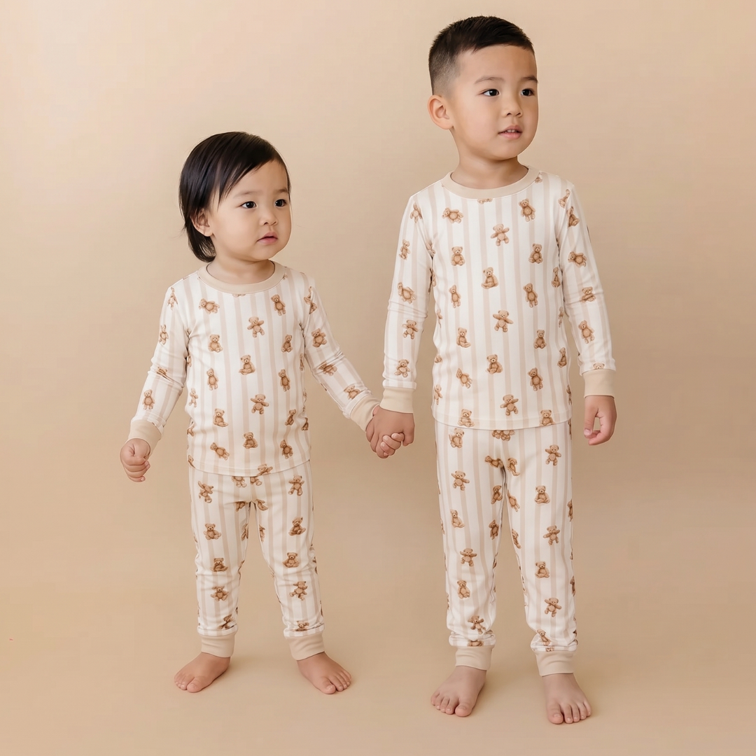 Two children wearing matching pajamas with a bear pattern on a beige background